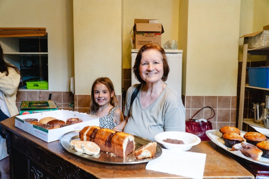 A woman and a girl behind a table of cakes