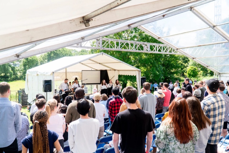 A summer gathering standing together under an open marquee
